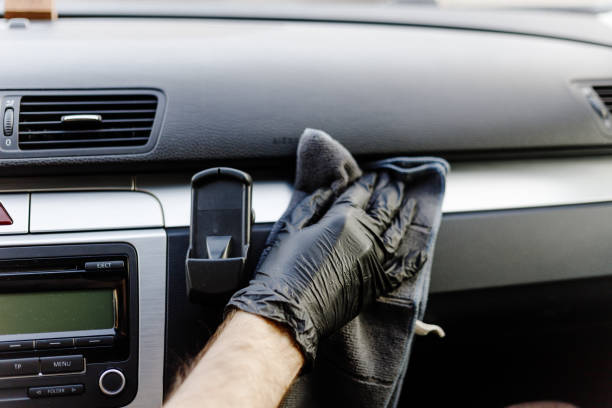 istock Man's hand in black glove cleaning car interior, dashboard and leather seats with microfiber cloth. Hand wipe down suede leather seat saloon interior. 1744855764