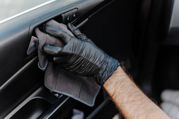 istock Man's hand in black glove cleaning car interior, dashboard and leather seats with microfiber cloth. Hand wipe down suede leather seat saloon interior. 1744855779