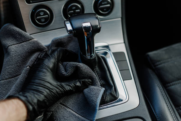istock Man's hand in black glove cleaning car interior, dashboard and leather seats with microfiber cloth. Hand wipe down suede leather seat saloon interior. 1744855780