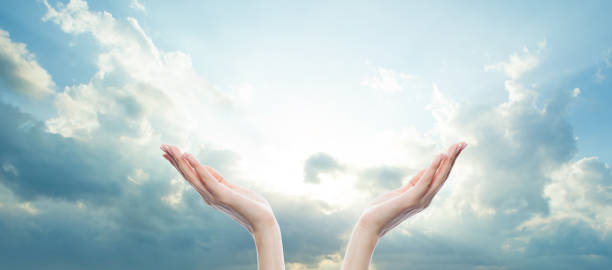 istock Two open female hands against blue sky with white cloud and sun light 1744860269