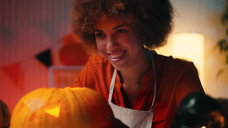 Happy African American woman in Halloween costume showing Jack-o-lantern pumpkin