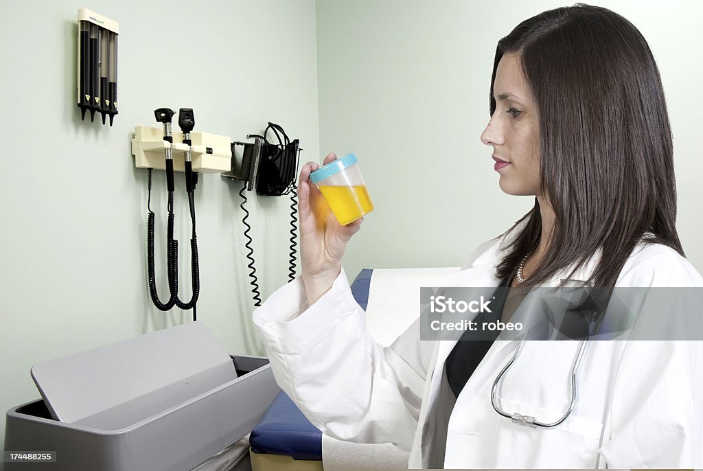 Woman Doctor with Urine Sample A beautiful young woman doctor holding a urine sample Adult Stock Photo