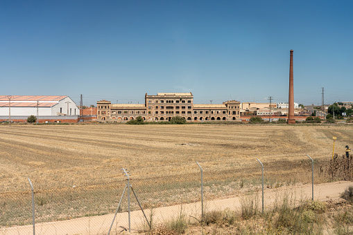 Old abandoned factory with new warehouses around it in a Spanish countryside. Castilla la Mancha. Spain. July 29, 2023.