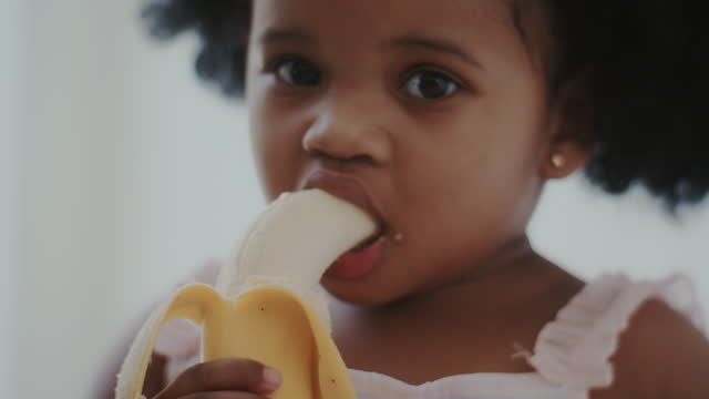 Baby girl eating a banana