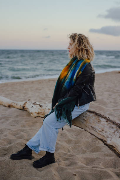 istock Woman sitting on the log at the beach 1744889440