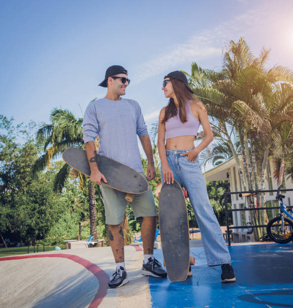 un jeune couple heureux avec des planches à roulettes profite du longboard au skatepark - 18809 photos et images de collection