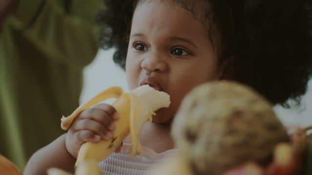Hungry messy toddler girl eating a banana