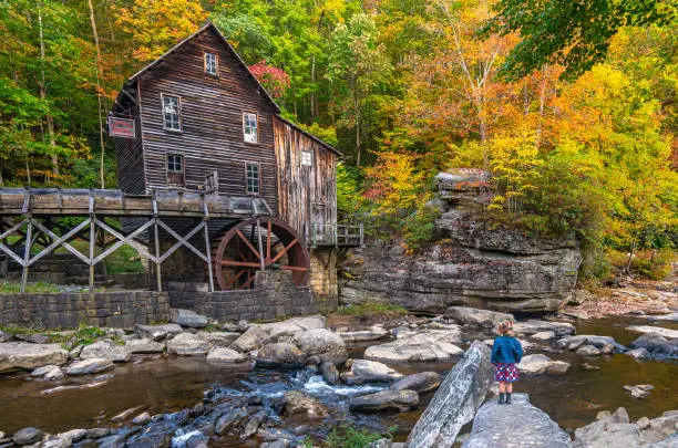 Young girl exploring the Glade Creek Grist Mill in Babcock State Park during the fall season in the Appalachian Mountains of West Virginia, USA.
