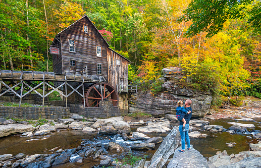 Father and daughter exploring the Glade Creek Grist Mill in Babcock State Park during the fall season in the Appalachian Mountains of West Virginia, USA.