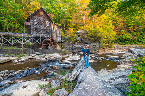 Father and daughter exploring the Glade Creek Grist Mill in Babcock State Park during the fall season in the Appalachian Mountains of West Virginia, USA.