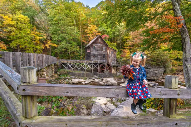 Young girl exploring the Glade Creek Grist Mill in Babcock State Park during the fall season in the Appalachian Mountains of West Virginia, USA.