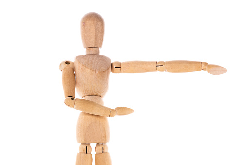 A wooden mannequin pointing at something. This image can be used as a visual representation of direction or guidance.