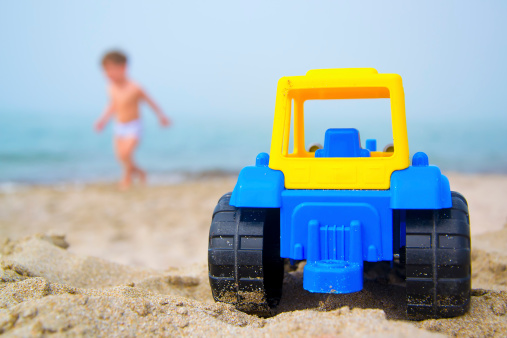 Toy tractor on the seashore, little boy on background