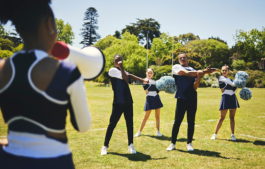Cheerleading team, coach and megaphone for practice, stretching and sports field for dancing, cheering and support. Training, warm up and outdoor for exercise together, competition and leadership