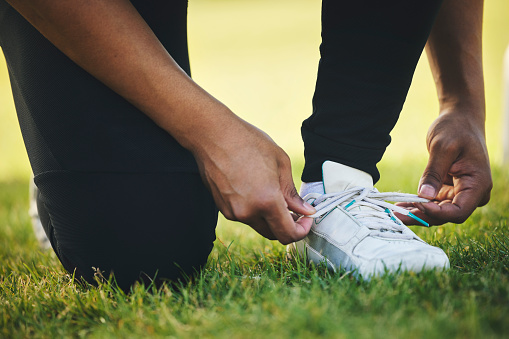 Person, hand and shoes for competition in sports on field for workout, practice or game in closeup. Athlete, dedication and motivation for winning with commitment for tournament, performance or match