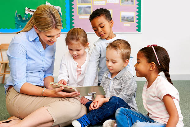 istock Teacher and preschooler reading book 174494907