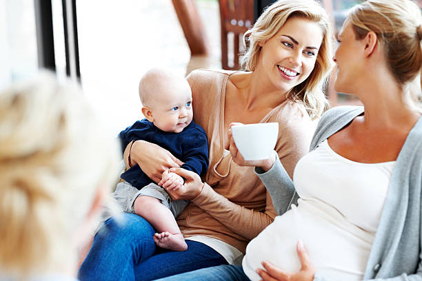 Happy pregnant woman with her friends relaxing at home Happy pregnant woman with her friends relaxing at home - Indoors group of babies stock pictures, royalty-free photos & images