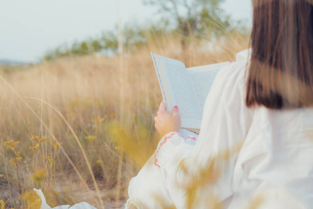 istock Woman with a book reading on a meadow at sunset 1744957601