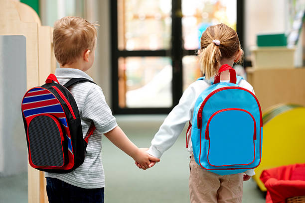 Young children walking to school Two cute little children walking to school - Rear view satchel stock pictures, royalty-free photos & images