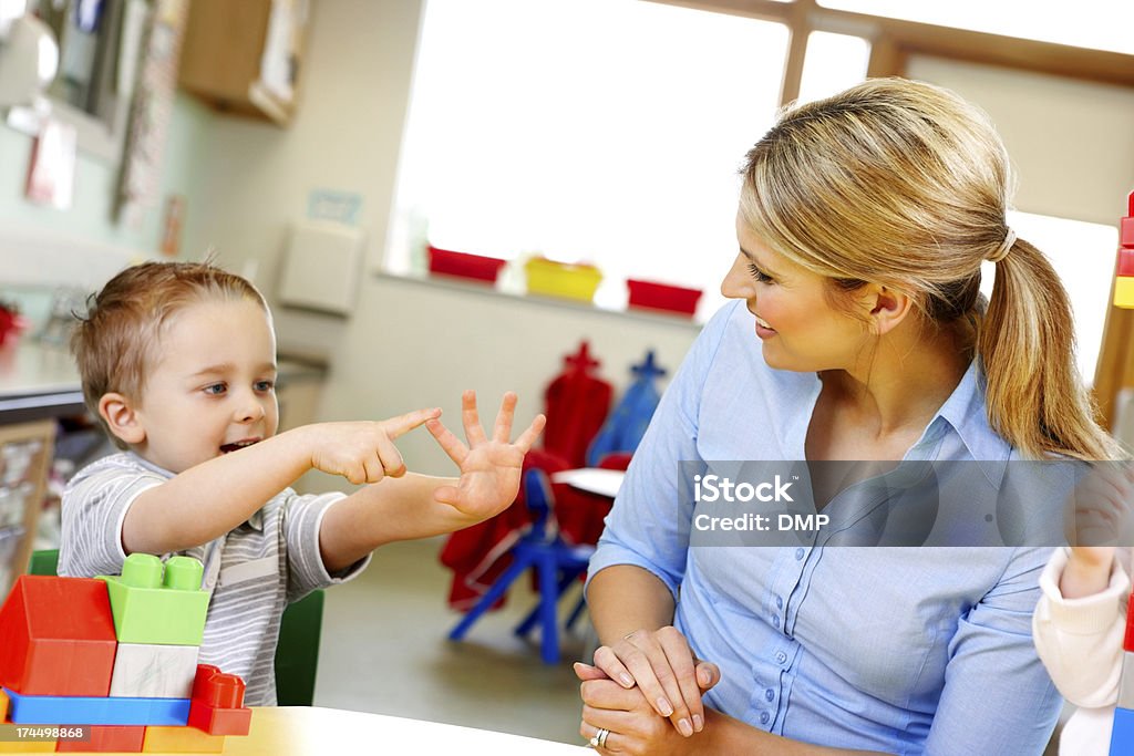 Carino piccolo bambino con insegnante in sala giochi giocando - Foto stock royalty-free di Bambino
