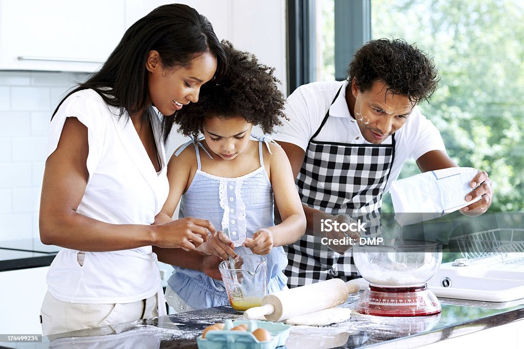 Couple baking with daughter Happy young couple with their little daughter baking together in kitchen Cooking Stock Photo