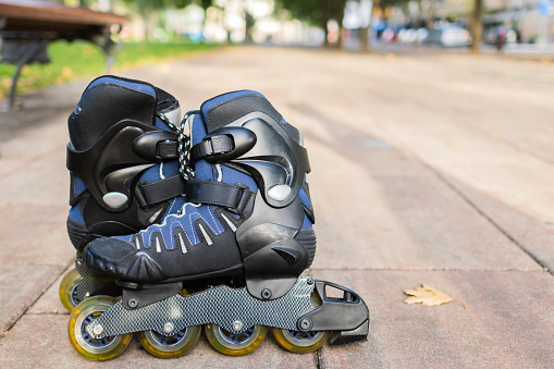 A pair of inline roller skates in park at sunset.