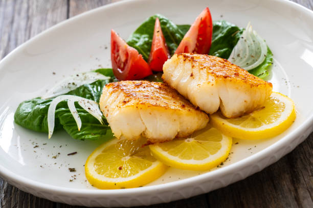 istock Fried cod fillet and fresh vegetables on wooden table 1745025459