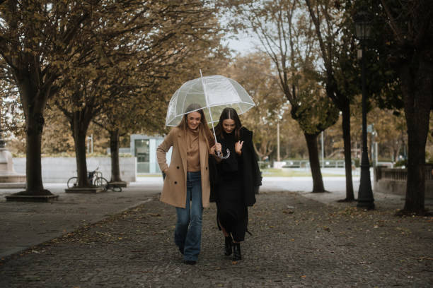 two women only walking under an umbrella - wet places imagens e fotografias de stock