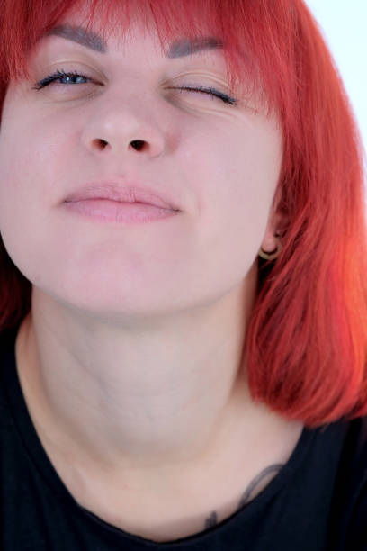 A young attractive woman with a short orange hairstyle in a black T-shirt and jeans posing in the studio on a white background.