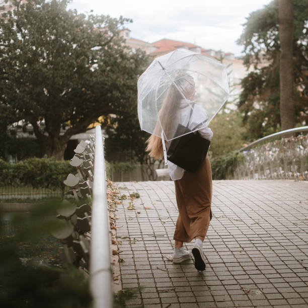 Rear view of a young woman with an umbrella in a city park