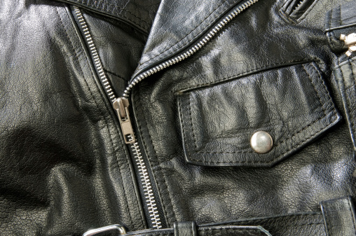 Detail image of a black leather motorcycle jacket. There are multiple highlights shinning across the jacket showing off is lustrous sheen. Useful image for any motorcycle theme.