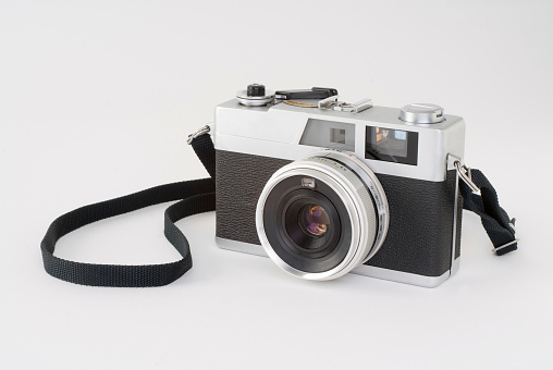 Digital mirrorless professional camera on wooden table with concrete wall as a background