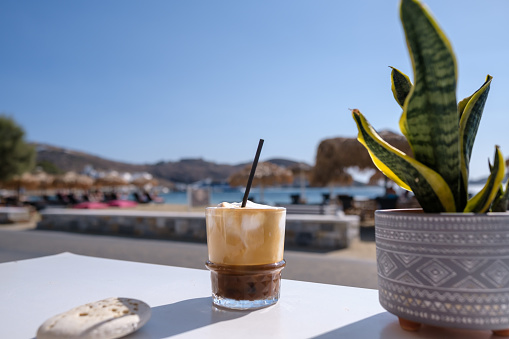 Closeup view of an iced greek  coffee, also known as freddo cappuccino with a straw in Ios Greece