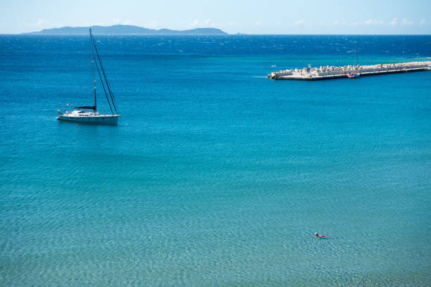September 12th 2022 - Ereikoussa, Greece - Sailboat and swimmer in Ereikoussa island, Greece