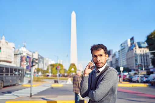 portrait latin american businessman talking on the cell phone on the street