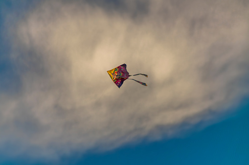 Color kite with blue sky and white clouds in sunny nice autumn windy evening