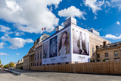 Paris, France - October 19, 2023: Giant advertising billboard for Celine, a French luxury ready-to-wear and leather goods brand, covering the restoration works of the Ecole Militaire building in Paris