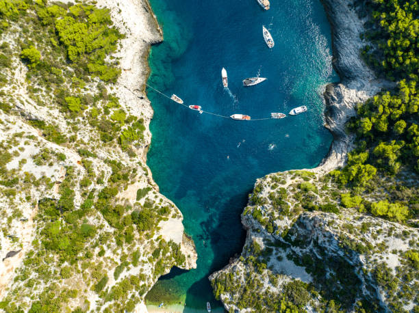 Top down view of Stiniva beach on Vis Island. Rocky cove and boats moored in the bay in Croatia catamaran sailing stock pictures, royalty-free photos & images