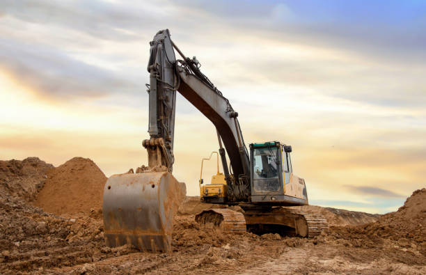 istock Excavator during earthmoving at construction site. Backhoe digging the ground for the foundation and for laying sewer pipes district heating. Earth-moving heavy equipment 1745180597