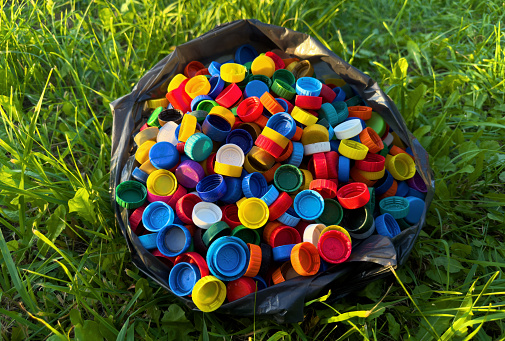 Plastic collecting for recycling. Plastic caps and Lids plastic bottles in garbage bag for recycling. PET Water bottles and PET Bottle Caps is recyclable and Reinventing.  Plastic waste collected.