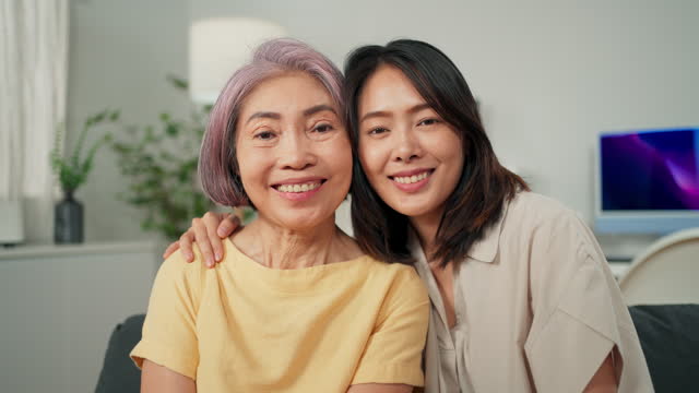Portrait of happy senior woman and beautiful woman smiling and looking camera with happiness sitting in living room at home