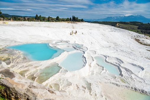 White terraces (natural travertine formations and hot pools) in Pamukkale, Turkey. The terraces are made of travertine, a sedimentary rock deposited by mineral water from the hot springs.