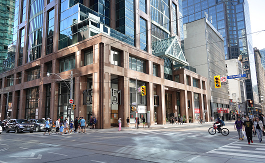 Toronto, Canada - August 27, 2023: Looking southeast as pedestrians and cyclists cross the intersection at the 100-block of Yonge Street at Richmond Street on a summer morning.