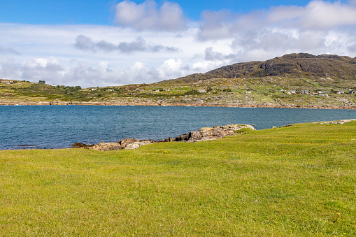 Beach with grass, rocks and mountain  in background, Dogs bay, Roundstone, Conemara, Galway, Ireland