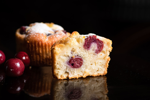 Freshly baked muffins with cherries from the compote on a black background. Front view
