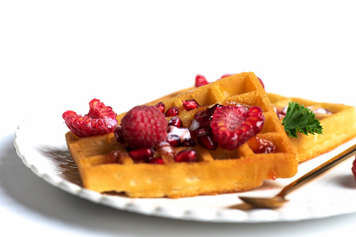 Belgian waffles with raspberries on a white plate isolated on white