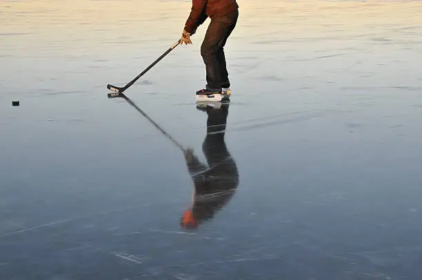 Playing icehockey. Head only visible in reflection. Evening sun.