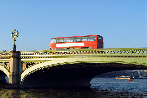 A double decker red London bus crossing wetminster bridge on a crisp winters morning.