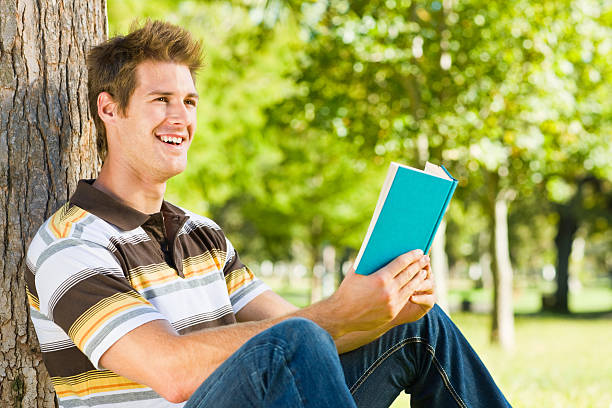 istock Young man reading book at park 174531045
