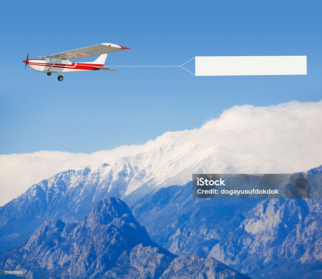 A small airplane towing a banner over a mountain landscape with private plane Airplane Stock Photo
